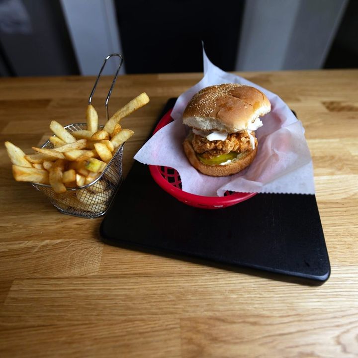 Burger and fries in a wire basket on a wood table
