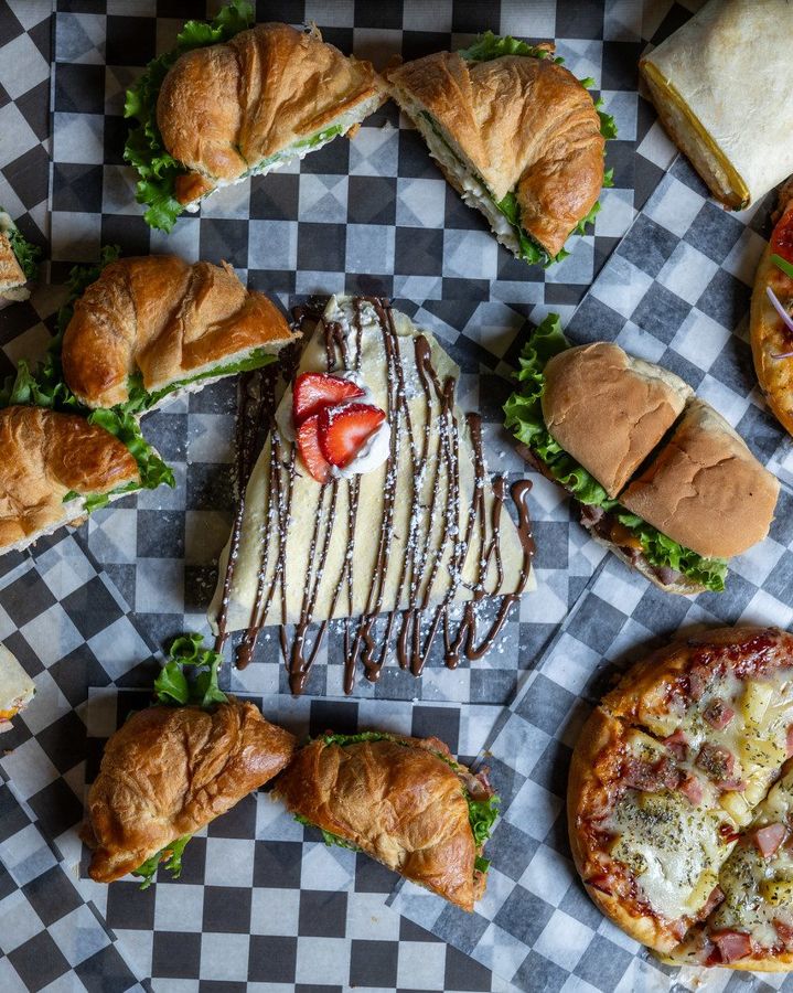 Sandwiches, croissants and pizzas laid out on checkered paper