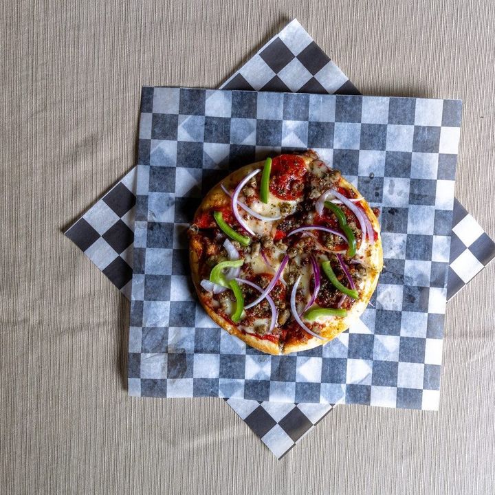 Loaded pizza on checkered paper, shot from above