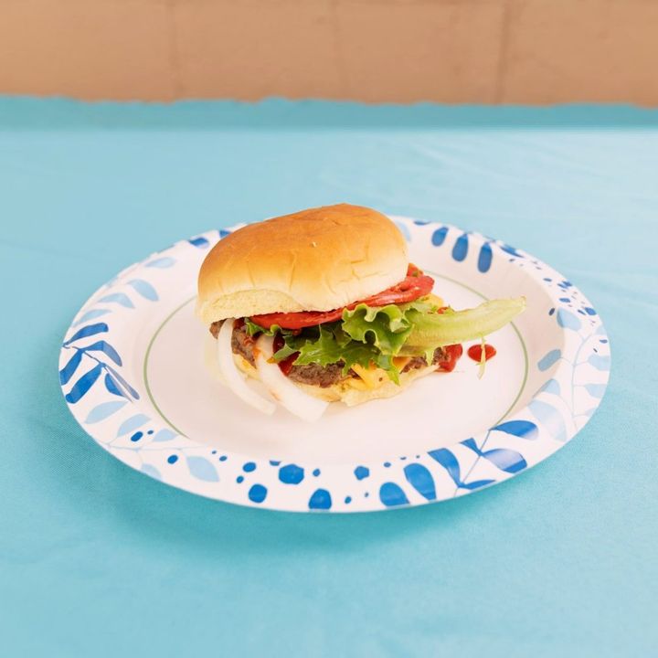 Burger with lettuce and tomato on a paper plate