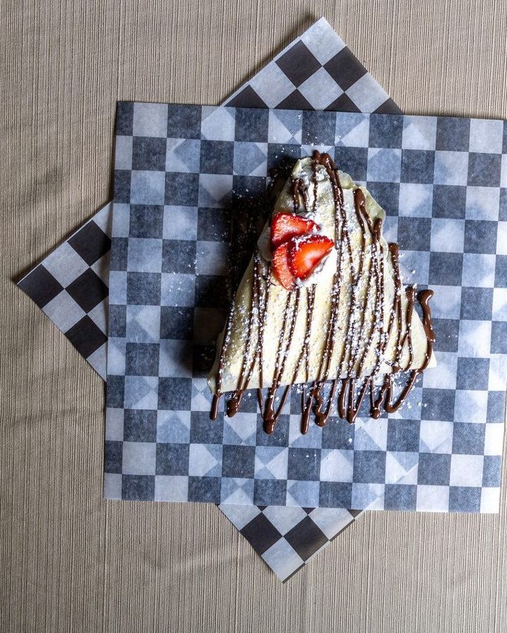 Slice of layered dessert with strawberries and chocolate drizzle