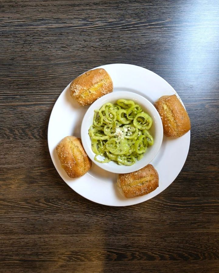 Pesto pasta with garlic knots on a dark wood table