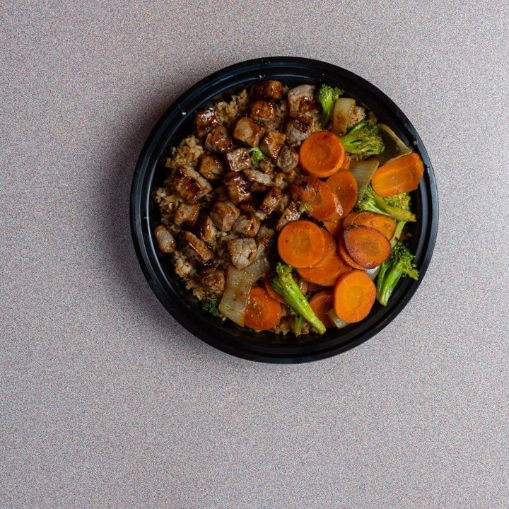 Stir-fry with carrots and greens in a black bowl
